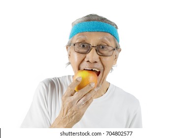 Photo Of An Old Man Wearing Sportswear While Eating An Organic Apple, Isolated On White Background