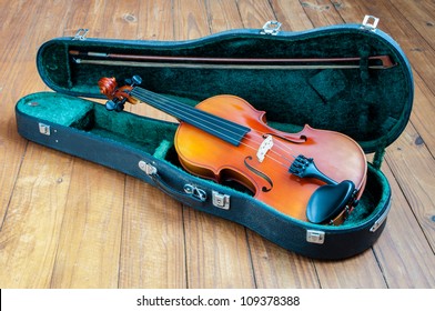 Photo of old violin in case on a wooden floor