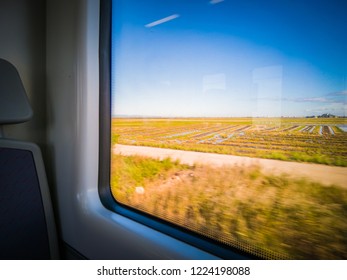 A photo of one of the comfortable seats of a high speed commuter rail train running in the C1 line direction to Valencia Nord train station. The window shows the beautiful natural park The Albufera.