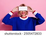 Photo of optimistic blonde lady hiding her eyes demonstrating futuristic design 3d hologram phone display isolated on pink color background