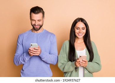 Photo of optimistic brunette nice couple look telephone wear sweater isolated on beige color background