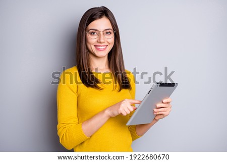 Photo of optimistic brunette nice lady hold tablet wear eyewear yellow sweater isolated on grey color background