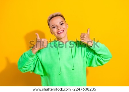 Photo of optimistic lady youngster hipster wear green trendy hoodie showing like symbol thumbs up recommend ad isolated on yellow color background
