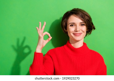 Photo of optimistic nice brunette hairdo lady show okey wear red sweater isolated on bright green color background