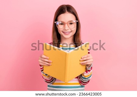 Photo of optimistic small learner student preteen schoolgirl reading copybook wear eyeglasses specs isolated on pink color background