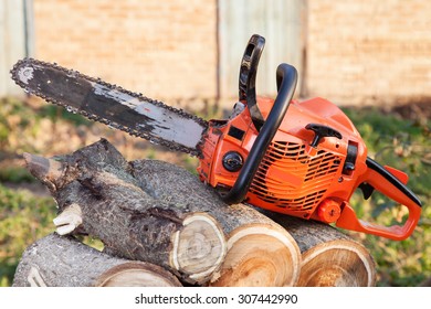 Photo orange chainsaw on heap firewood outdoors