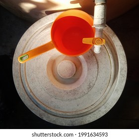 Photo Of An Orange Dipper, A Water Faucet With An Orange Handle, And A Dull White Bucket Lid At The Daylight. Equipment In The Kitchen. View From Above. Focus On
Foreground.