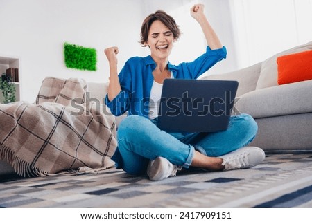 Photo of overjoyed cheerful glad girl with raised hands fists celebrate victory achievements indoors