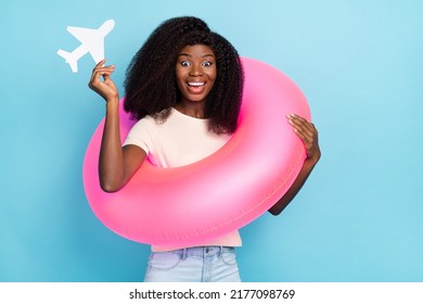 Photo Of Overjoyed Positive Girl Wear Inflatable Ring Hold Small Paper Airplane Isolated On Blue Color Background