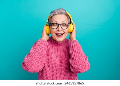 Photo of overjoyed woman wear pink sweater in glasses touch headphones inpressed by sound quality isolated on teal color background - Powered by Shutterstock