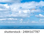 A photo of a parachute and a photo of a skydiver in the air. A skydiver in flight.