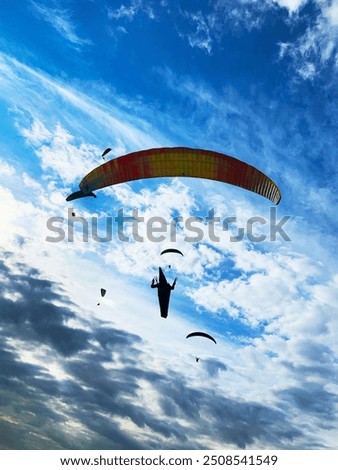 
photo of paraglider flying on a blue sky day with clouds 