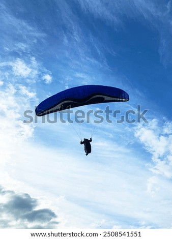 
photo of paraglider flying on a blue sky day with clouds 