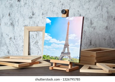 Photo of Paris printed on canvas, a wooden easel and stretcher bars on table - Shutterstock ID 1326795785