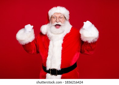 Photo of pensioner grandpa grey beard raise fists open mouth win achievement best santa event wear costume leather belt gloves coat spectacles headwear isolated red color background