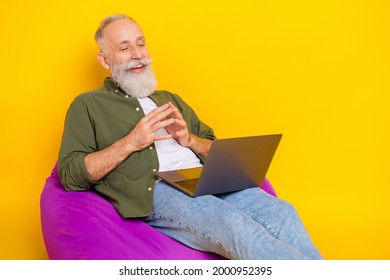 Photo Of Pensioner Man Sit Beanbag Hold Computer Look Screen Wear Green Shirt Isolated Yellow Color Background