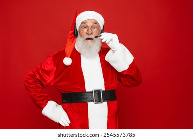 Photo of pensioner old man grey beard Santa Clause in headset talk collegue elves find out good news wear x-mas santa costume gloves coat belt cap eyeglasses isolated red color background - Powered by Shutterstock