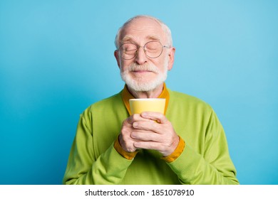 Photo Of Pensioner Old Man Hold Cup Eyes Closed Sniff Aroma Wear Eyeglasses Green Pullover Isolated Blue Color Background