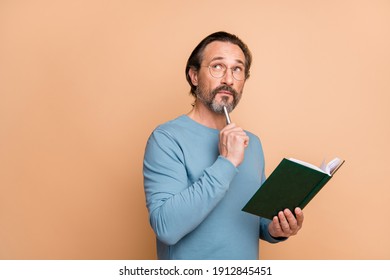 Photo of pensive smart man hold pen notepad look empty space wear specs blue sweater isolated beige color background - Powered by Shutterstock