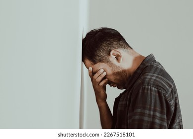 photo of person leaning his head against a wall, worried, stressed, with many problems, pensive, resigned, frustrated. Concept of lifestyles, problems, societal problems. - Powered by Shutterstock