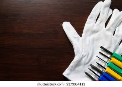 Photo of Phillips and flathead screwdrivers, tools, white gloves and wooden background