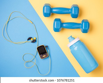 Photo of player, dumbbells, bottle of water on blue and yellow background - Shutterstock ID 1076781251