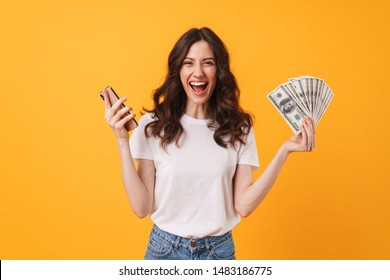Photo of pleased happy screaming young woman posing isolated over yellow wall background using mobile phone holding money. - Shutterstock ID 1483186775