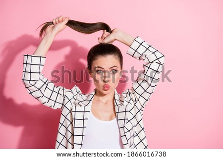 Photo portrait of adorable girl playing with hair isolated on pastel pink colored background