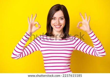 Photo portrait of adorable young girl smiling show double okey symbol wear trendy striped clothes isolated on yellow color background