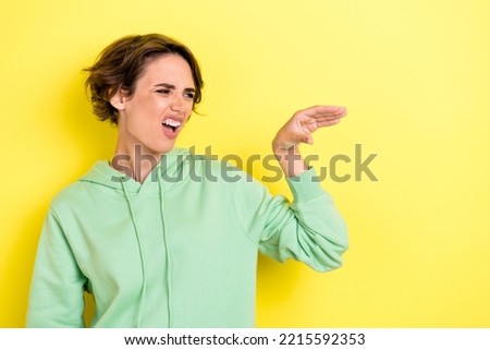 Photo portrait of adorable young woman irritated teasing talking hand blah dressed stylish green outfit isolated on yellow color background