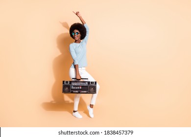 Photo portrait of african american woman holding boombox pointing one finger up dancing isolated on pastel beige colored background