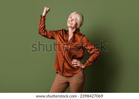 Photo portrait of attractive pensioner woman fists muscles confident dressed stylish silk brown clothes isolated on khaki color background