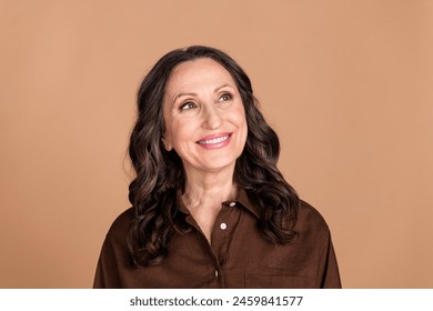 Photo portrait of attractive senior woman look empty space dressed stylish brown clothes isolated on beige color background - Powered by Shutterstock