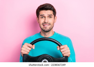 Retrato fotográfico de un joven atractivo sosteniendo el volante morder los labios confundidos usar ropa de moda azul aislado en el fondo de color rosa