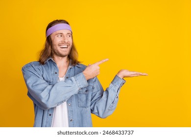 Photo portrait of attractive young hippie man point look palm hold empty space wear trendy denim outfit isolated on yellow color background - Powered by Shutterstock