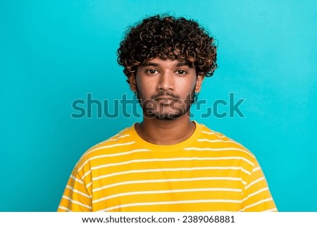 Photo portrait of attractive young man indifferent look camera dressed stylish striped yellow clothes isolated on cyan color background