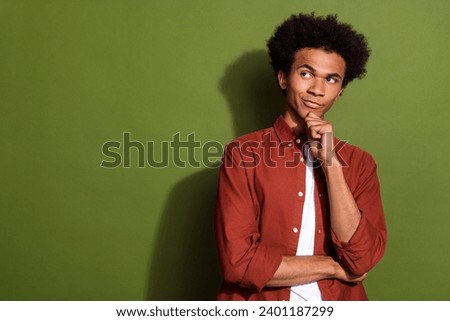 Photo portrait of attractive young man touch chin look tricky empty space dressed stylish brown clothes isolated on khaki color background