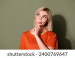 Photo portrait of attractive young woman look interested empty space dressed stylish orange clothes isolated on khaki color background
