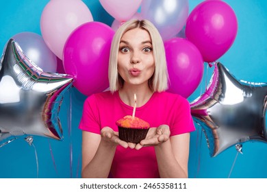 Photo portrait of attractive young woman air balloons cupcake blow candle dressed stylish pink clothes isolated on blue color background - Powered by Shutterstock