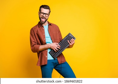 Photo portrait of bearded man keeping keyboard playing like guitar isolated on bright yellow color background