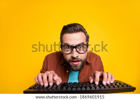 Photo portrait of bearded student playing video game crazy geek with keyboard in glasses isolated on vibrant yellow color background