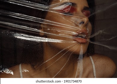 Photo Portrait Of Brunette Woman Wearing Make-up Breathing Behind Transparent Cellophane Covered With Water Drops