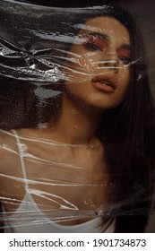 Photo Portrait Of Brunette Woman Wearing Make-up Breathing Behind Transparent Cellophane Covered With Water Drops