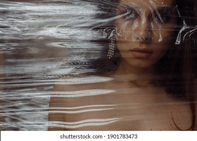 Photo Portrait Of Brunette Woman Wearing Make-up Breathing Behind Transparent Cellophane Covered With Water Drops