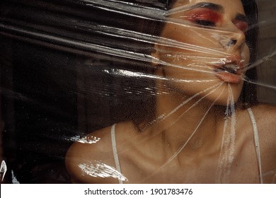 Photo Portrait Of Brunette Woman Wearing Make-up Breathing Behind Transparent Cellophane Covered With Water Drops