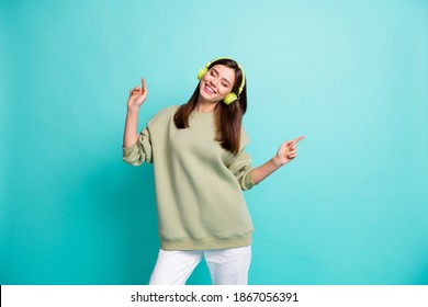 Photo Portrait Of Carefree Woman Dancing Listenting To Music In Green Earphones Isolated On Vivid Cyan Colored Background