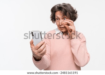 Photo portrait of caucasian surprised shocked amazed senior aged mature woman holding mobile phone seeing crazy discounts wearing casual clothes isolated on white background.