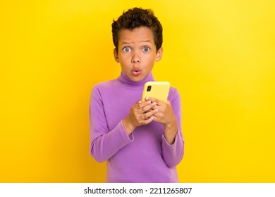 Photo portrait of charming small schoolboy hold gadget impressed news dressed stylish purple look isolated on yellow color background