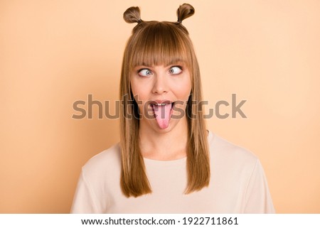 Photo portrait of childish crazy girl showing tongue grimacing wearing t-shirt isolated on pastel beige color background