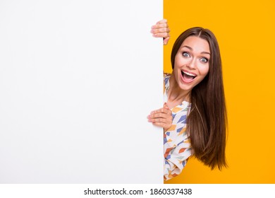 Photo portrait of crazy girl hiding behind white wall with blank space isolated on vivid yellow colored background